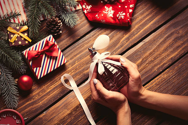 female hands holding perfume photo of the female hands holding perfume on the christmas decorations background perfume stock pictures, royalty-free photos & images