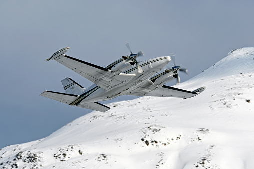 Photo of a Piper twin-engined turboprop aircraft taking-off with snowy mountain in the background
