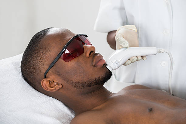 thérapeute donnant un traitement d’épilation au laser sur un jeune homme - massaging men beauty spa beauty treatment photos et images de collection