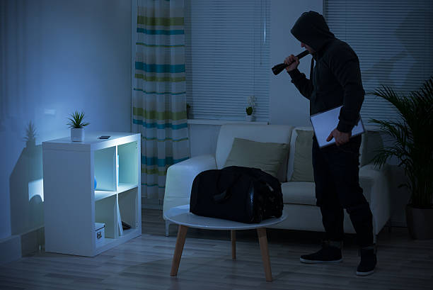 istock Thief Holding Flashlight At Shelves In Living Room 625889054