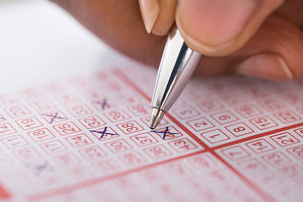 istock Person Marking Number On Lottery Ticket With Pen 625889726