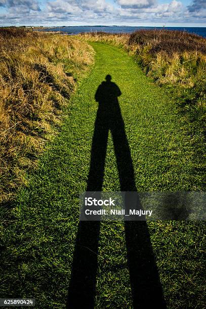Tall Shadow Of Man On Grass Path Stock Photo - Download Image Now - Men, Long Shadow - Shadow, Adult