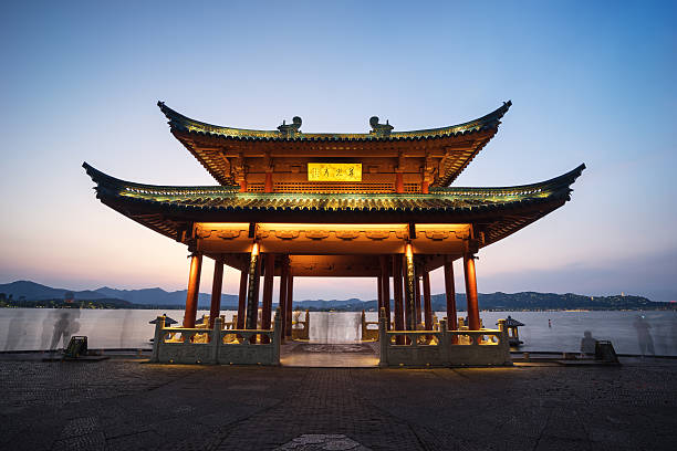 White Pagoda and Five Dragon Pavilions stand illuminated at night, their light reflecting on the calm waters of Beihai Park lake, showcasing traditional Chinese architecture