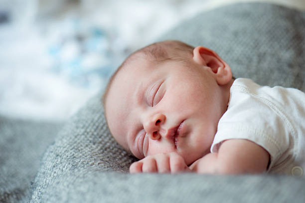 neugeborenes baby junge auf dem bett liegend, schlafend, aus nächster nähe - tranquil scene sleeping clothing expressing positivity stock-fotos und bilder