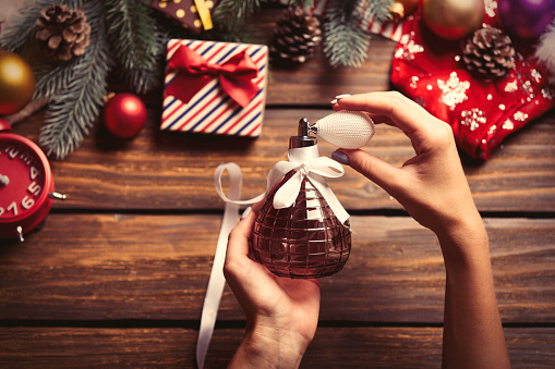 photo of the female hands holding perfume on the christmas decorations background