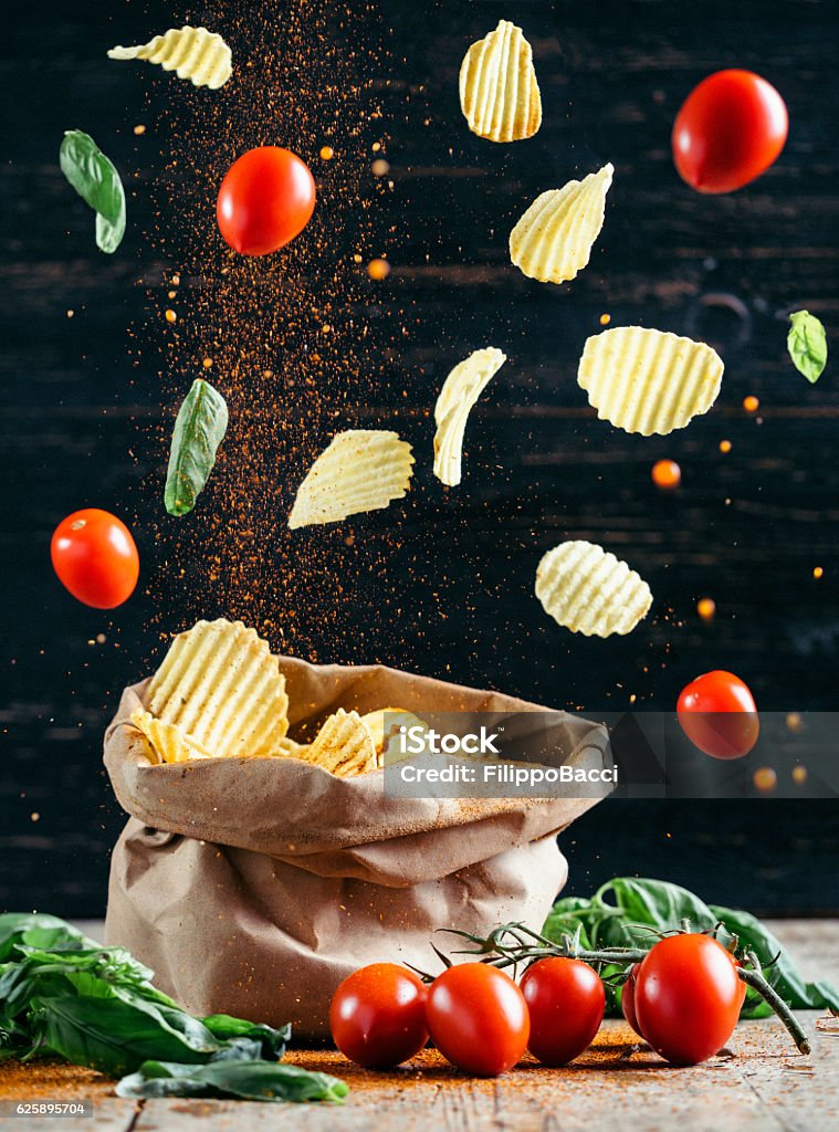 Flying Food - Chips And Tomatoes Studio shot of flying chips and tomatoes. Flying Stock Photo
