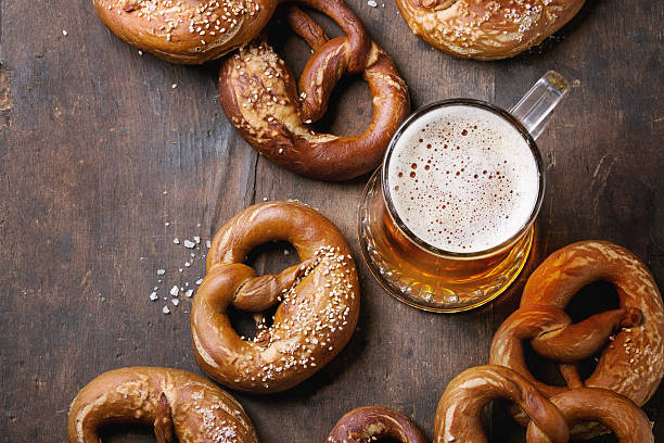 Lager beer with pretzels Glass of lager beer with traditional salted pretzels over old dark wooden background. Top view with space for text. Beer Fest theme oktoberfest beer stock pictures, royalty-free photos & images