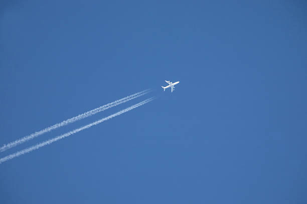 istock white jet airplane flying high in the blue sky 625896362