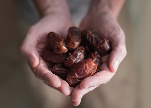 A man holds a selection of dates in his cupped hands