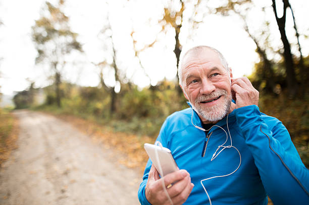 istock Senior runner in nature with smart phone with earphones. 625903798