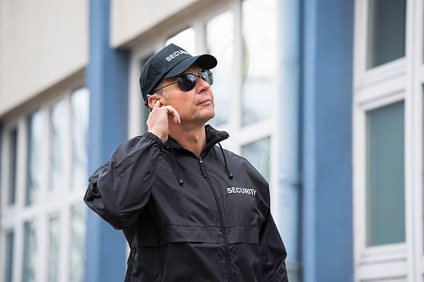 security guard using mobile phone outside building - beveiliger stockfoto's en -beelden