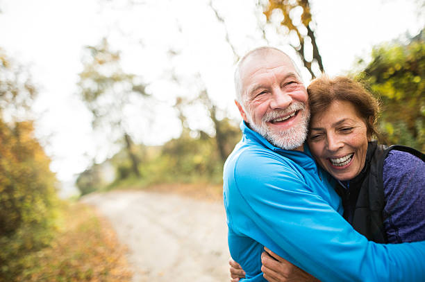 schönes seniorenpaar läuft draußen im sonnigen herbstwald - action senior adult lifestyles couple stock-fotos und bilder