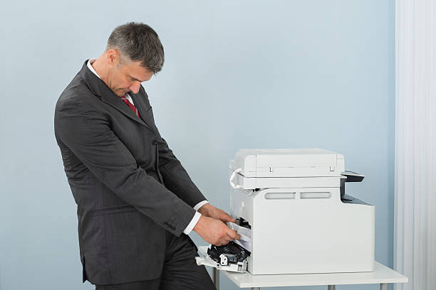 istock Businessman Removing Paper Stuck In Printer At Office 625905096