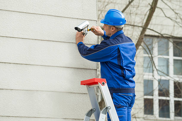 мужской техник, стоящий на stepladder fitting камеры видеонаблюдения - security camera installing security system security стоковые фото и изображения