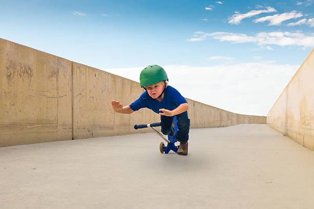 Little Boy Crashing His Scooter Down A Bike Path