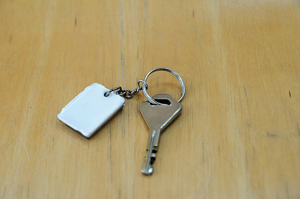 istock Single key with white key-chain on light wooden board 625913846