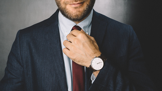 Smiling businessman fixing his necktie before going to work