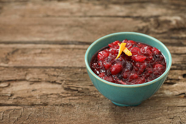 Freshly Made Cranberry Sauce A high angle close up horizontal photograph of a turquoise bowl full of freshly made Thanksgiving cranberry sauce garnished with pieces of orange tangerine peel. thanksgiving full stock pictures, royalty-free photos & images