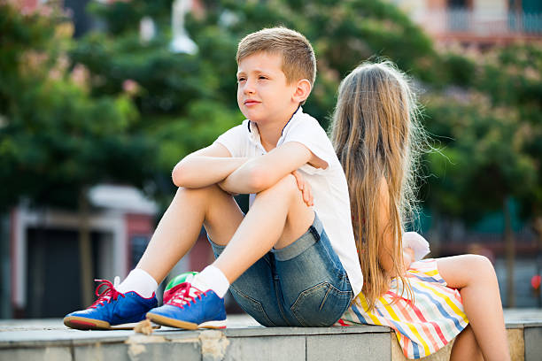 istock sad boy sitting back to friend outdoor 625928458