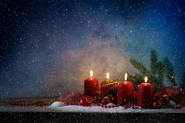 istock red advent candles burning, dark snowy background with copy space 625929292