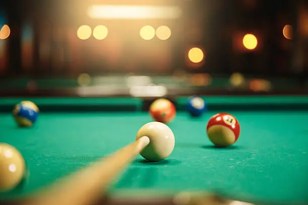 Preparing to break spheres into the pool pocket. Green cloth. Blur background.