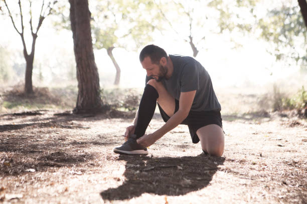 istock Young man tying his shoelaces in park 625938150