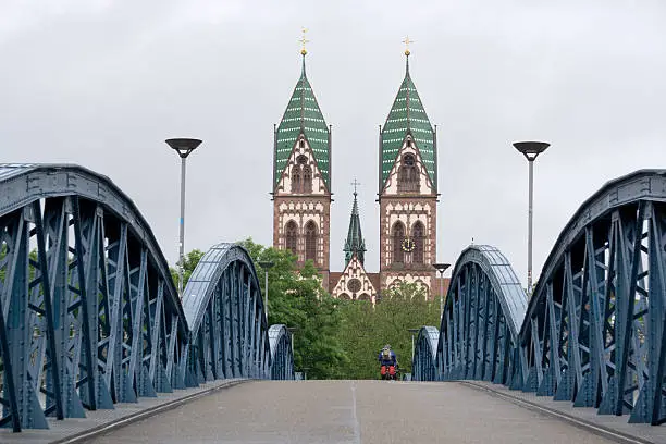 View of the Herz-Jesu-Kirche in Freiburg im Breisgau in Germany. In the foreground a blue iron bridge