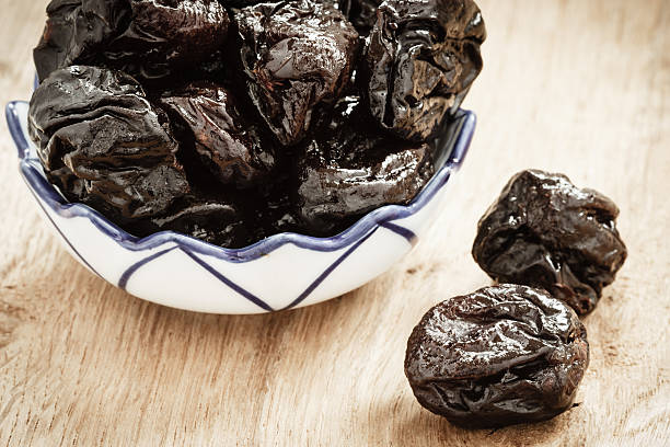 istock dried plums prunes in bowl on wooden table 625942866