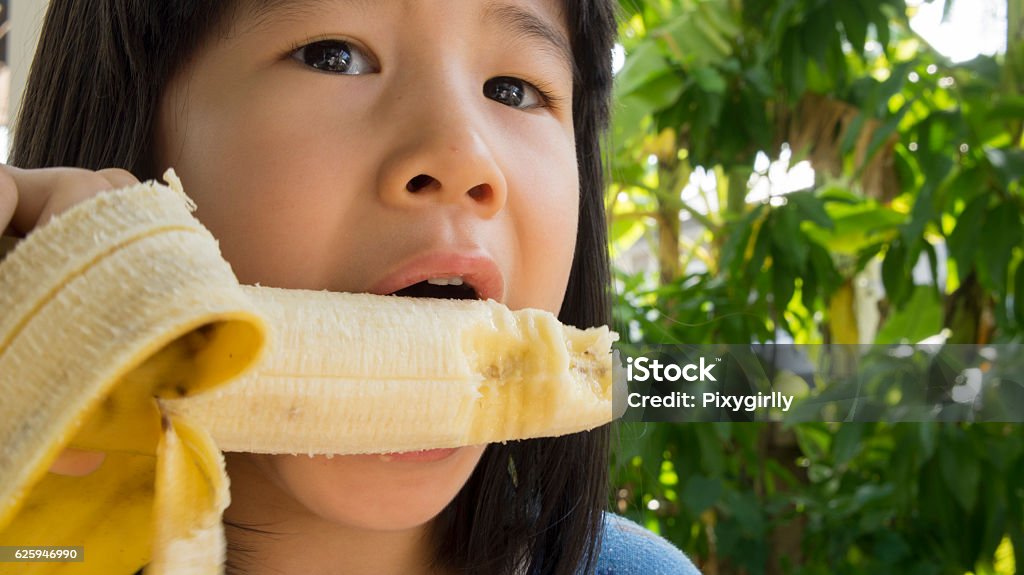 child eat banana asian joy chew bite concept - Royaltyfri Asiatiskt och indiskt ursprung Bildbanksbilder