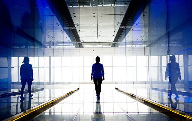 silhouette d’une femme d’affaires marchant dans la lumière - wall corridor tunnel glass photos et images de collection