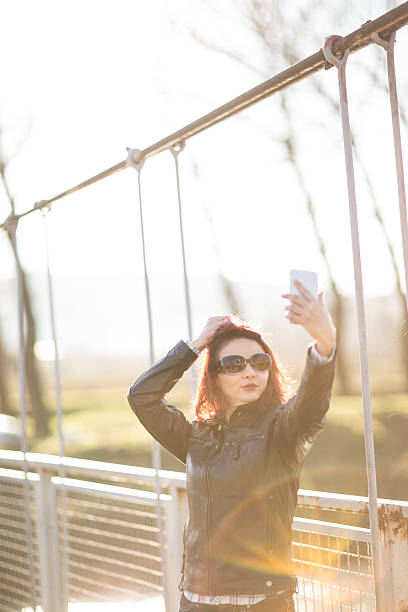 istock young woman on footbridge taking a selfie 625961742