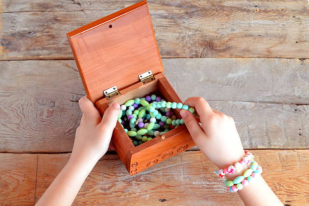 Little girl opens a box of bracelets. Old wooden background 