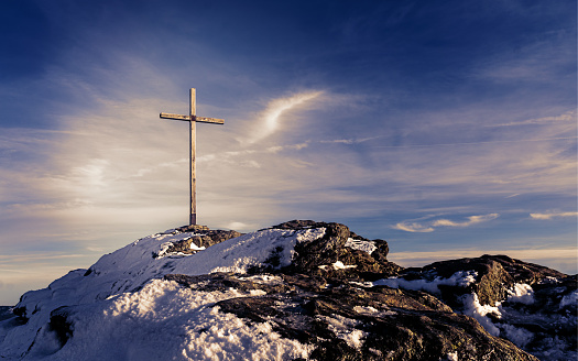 Wooden summit cross on the mountain peak with cloudy clear sky - Picture with mystic purple look