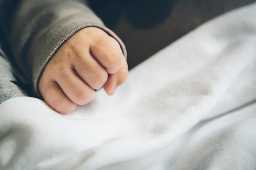 Small baby fist hand close up on a white sheet background