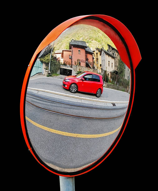 View of a traffic jam reflected in a car's side mirror on a rural road with trees and clear blue sky