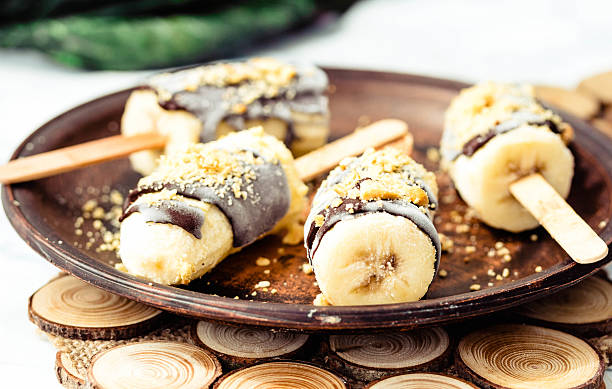 Frozen bananas with chocolate and nuts, raw summer dessert stock photo