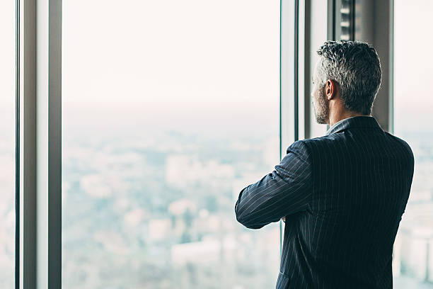 homme d'affaires dans un gratte-ciel - rear view businessman thinking men photos et images de collection