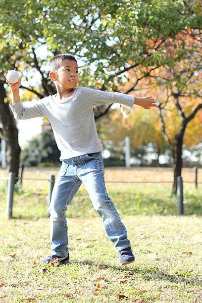 ragazzo giapponese che gioca a pesca - baseballs baseball grass sky foto e immagini stock