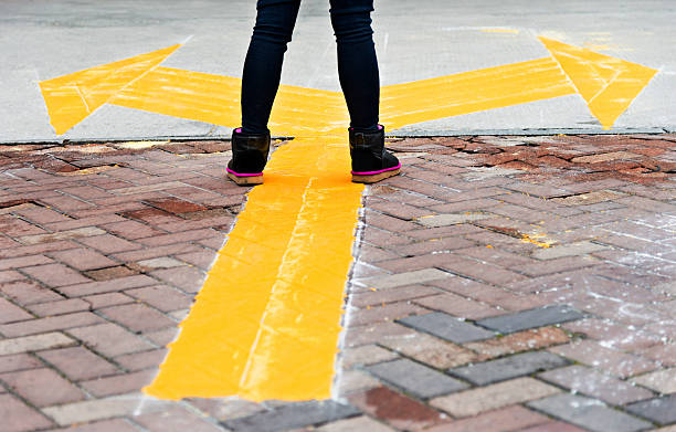 женщина, стоя на желтый направлении стрелки - brick yellow road footpath стоковые фото и изображения