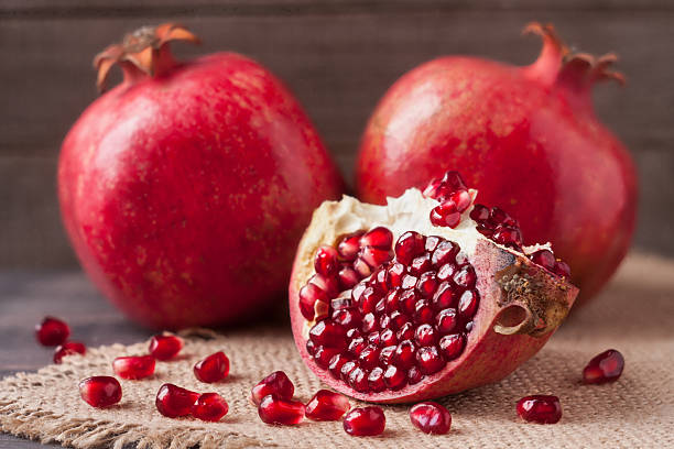 istock two pomegranate on the old wooden board with sackcloth 626000360