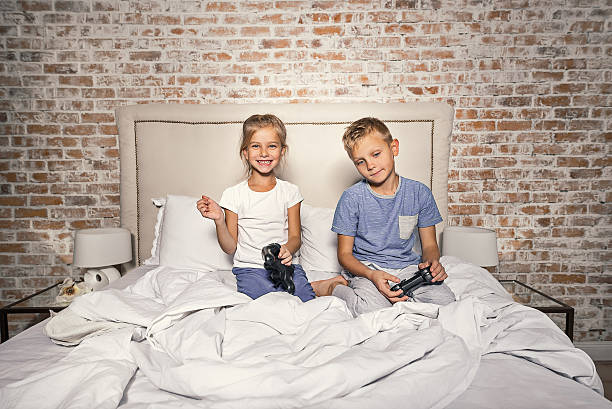 hermanos felices usando joystick en el dormitorio - video game child handheld video game little boys fotografías e imágenes de stock