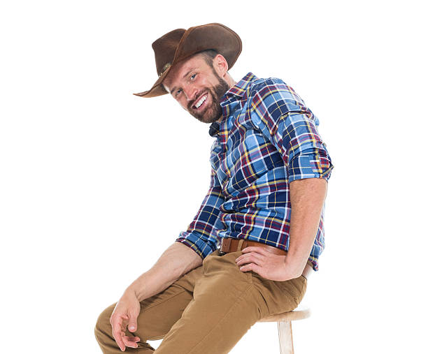 istock Cheerful cowboy sitting on stool 626002120