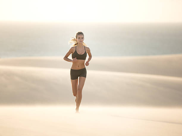 mulher atlética correndo sobre uma duna de areia, extreme fitness - triathlon ironman triathalon ironman people - fotografias e filmes do acervo