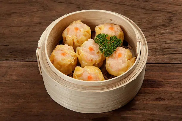 Chinese dim sum in a bamboo steamer box on a wood table