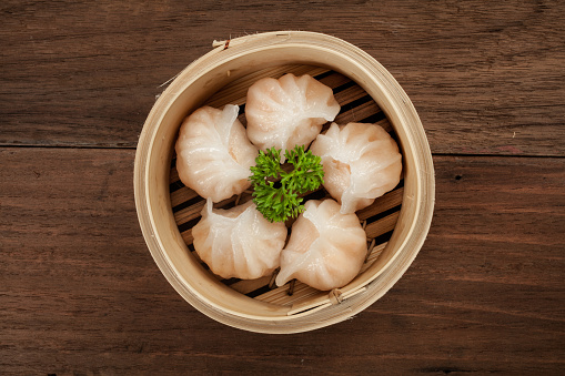 Chinese dumpling in a bamboo steamer box on a wood table