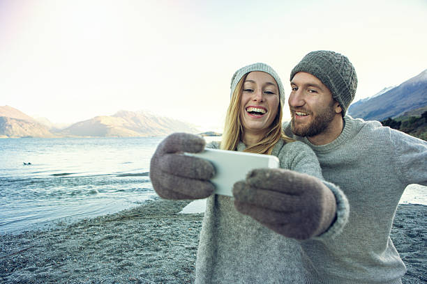 Young couple traveling take a selfie portrait using smart phone, spectacular landscape on the background.