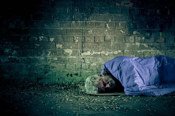 Photo of Senior homeless caucasian male sleeping rough outdoors