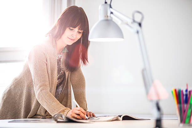 istock Young businesswoman analyzing brochure at table in office 626010674