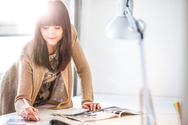 istock Young businesswoman analyzing brochures at table in office 626011278