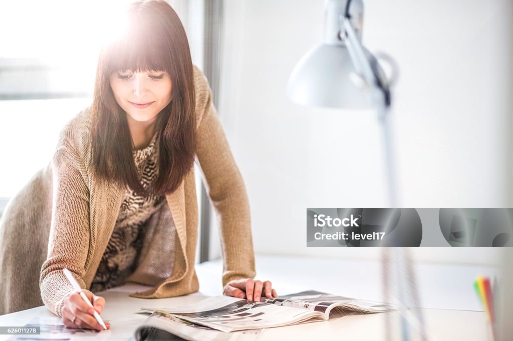 Young businesswoman analyzing brochures at table in office Interior Designer Stock Photo